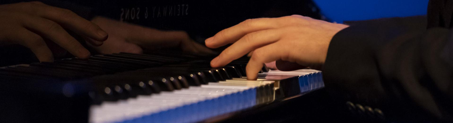 Hands playing a piano. 